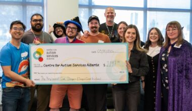A large group of people gather around a giant cheque for $2,147 made out to the Centre for Autism Alberta