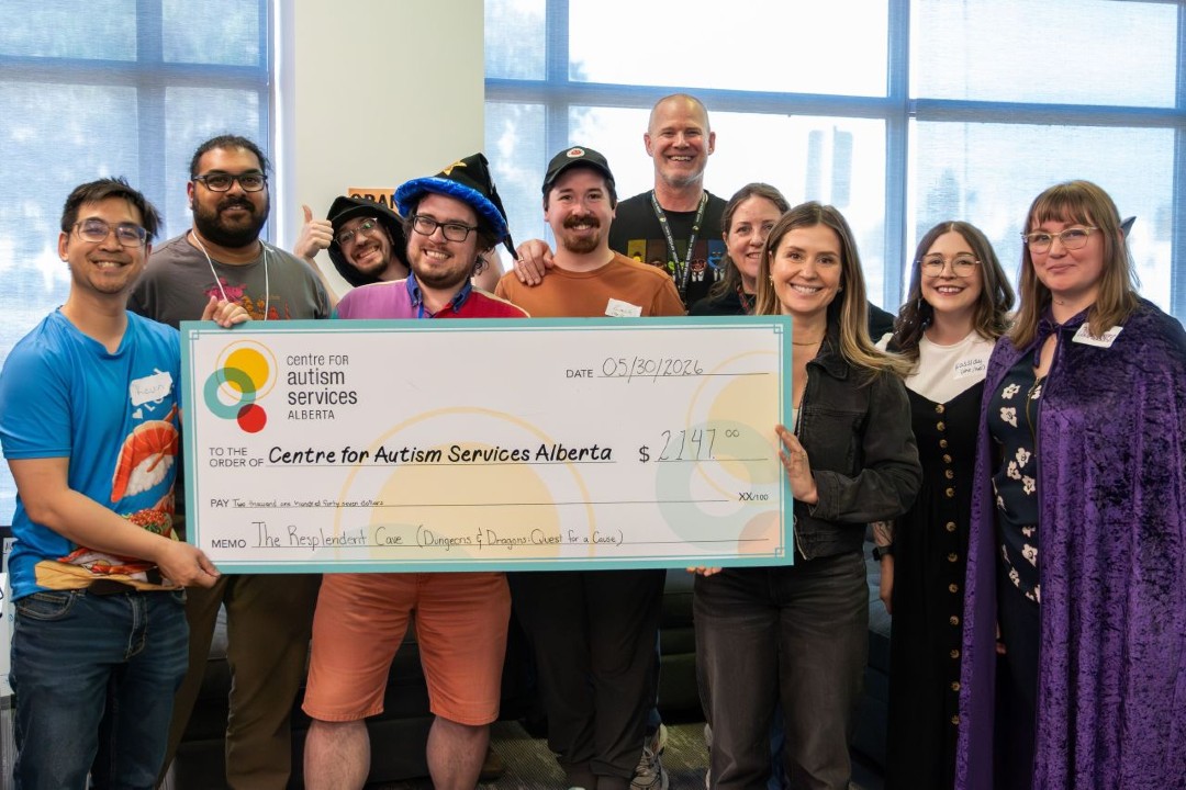 A large group of people gather around a giant cheque for $2,147 made out to the Centre for Autism Alberta