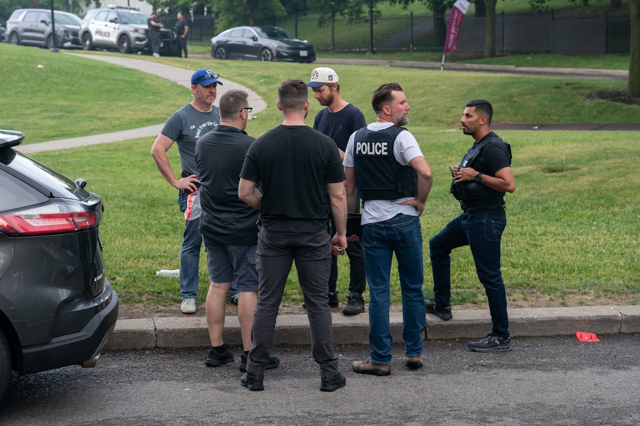 Police officers stand around a curb.