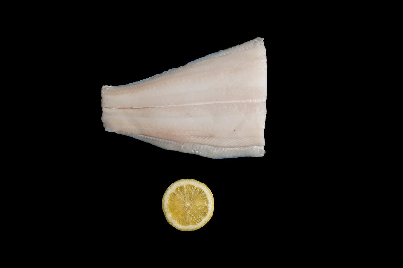 A marketing photo of a fish fillet with a lemon below, on a black background.