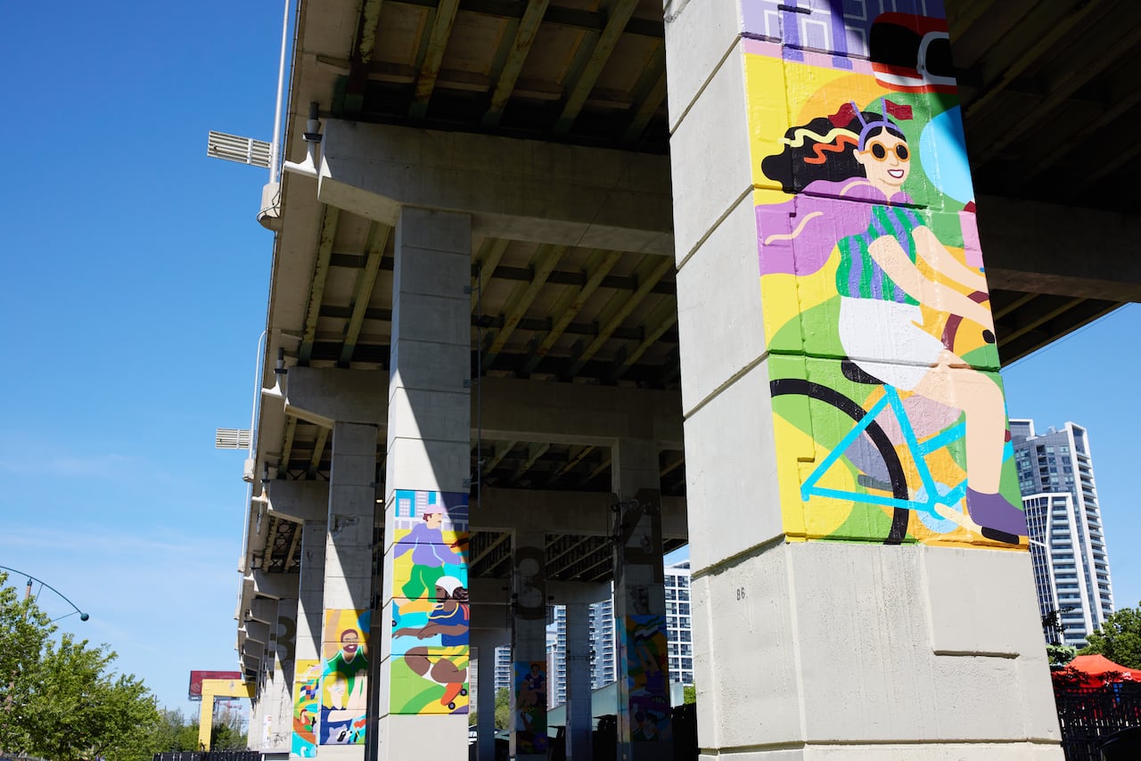 Murals of people cyclying, rollerskating and paddling on concrete pillars.