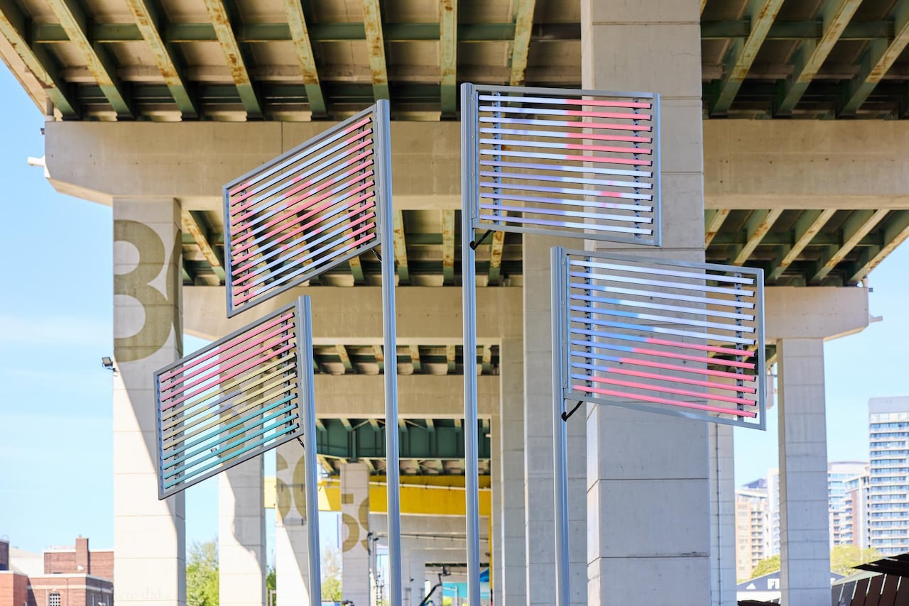 A light display of LEDs on poles, displaying the flags of Czechia, Panama, Canada, and Ghana. It is located under a highway.