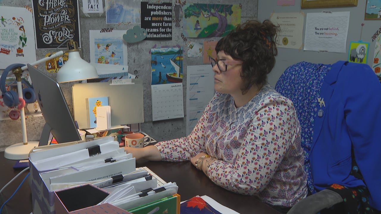 A woman wearing glasses sits at her desk while using her computer.