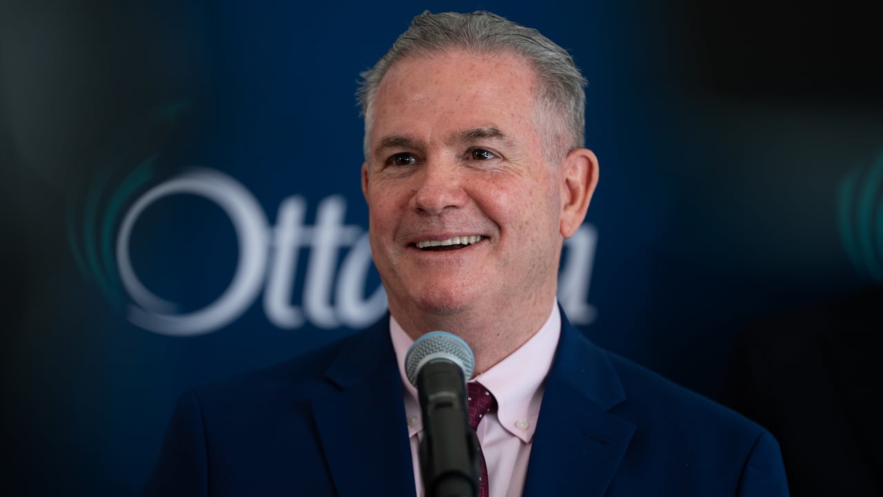 A man smiles behind a microphone during an announcement.