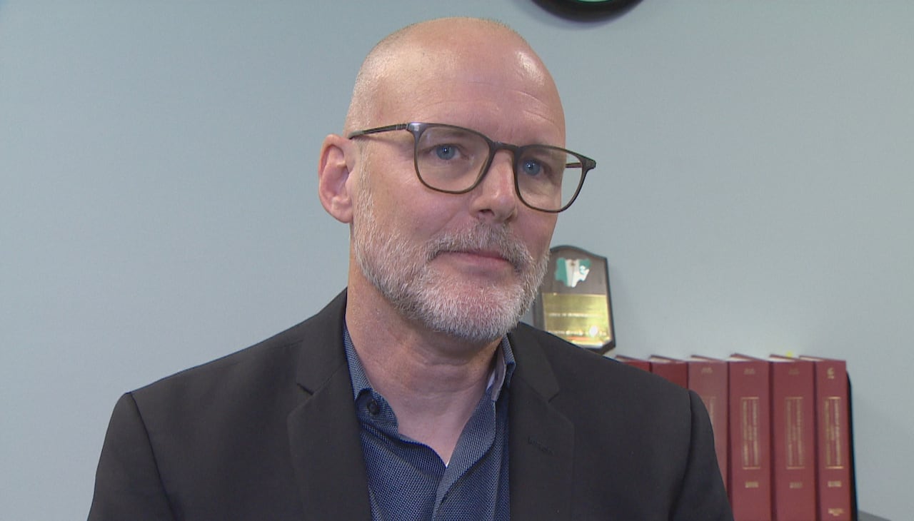A bald man with glasses and facial hair.