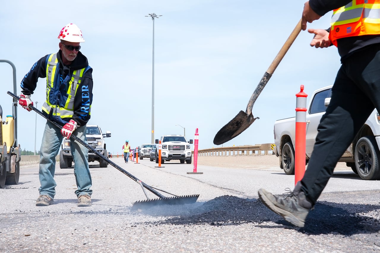 Volunteers fill potholes with asphalt on a road.