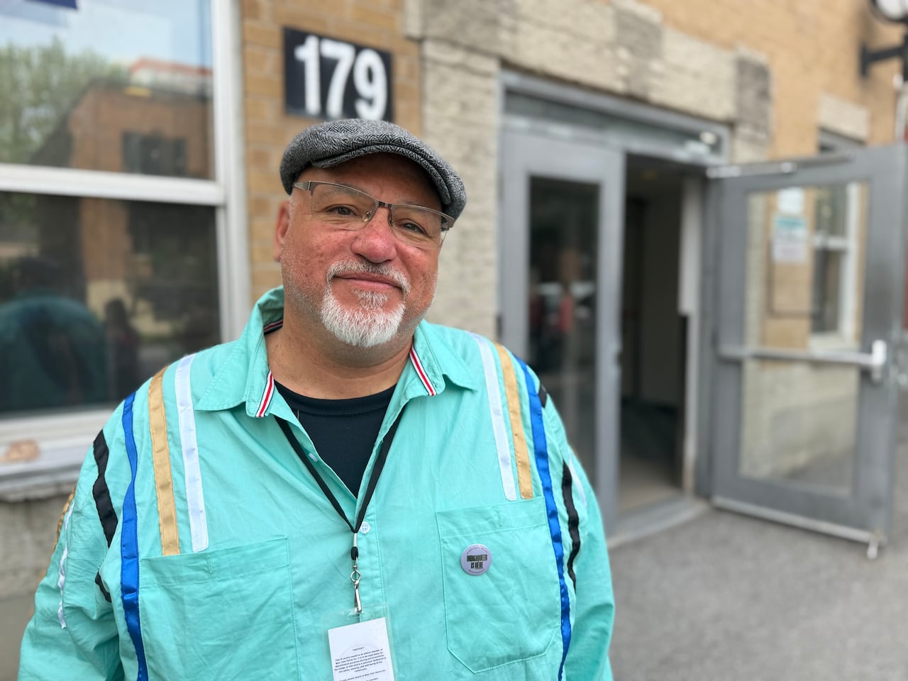 Man smiles wearing bright blue shirt and a grey hat.