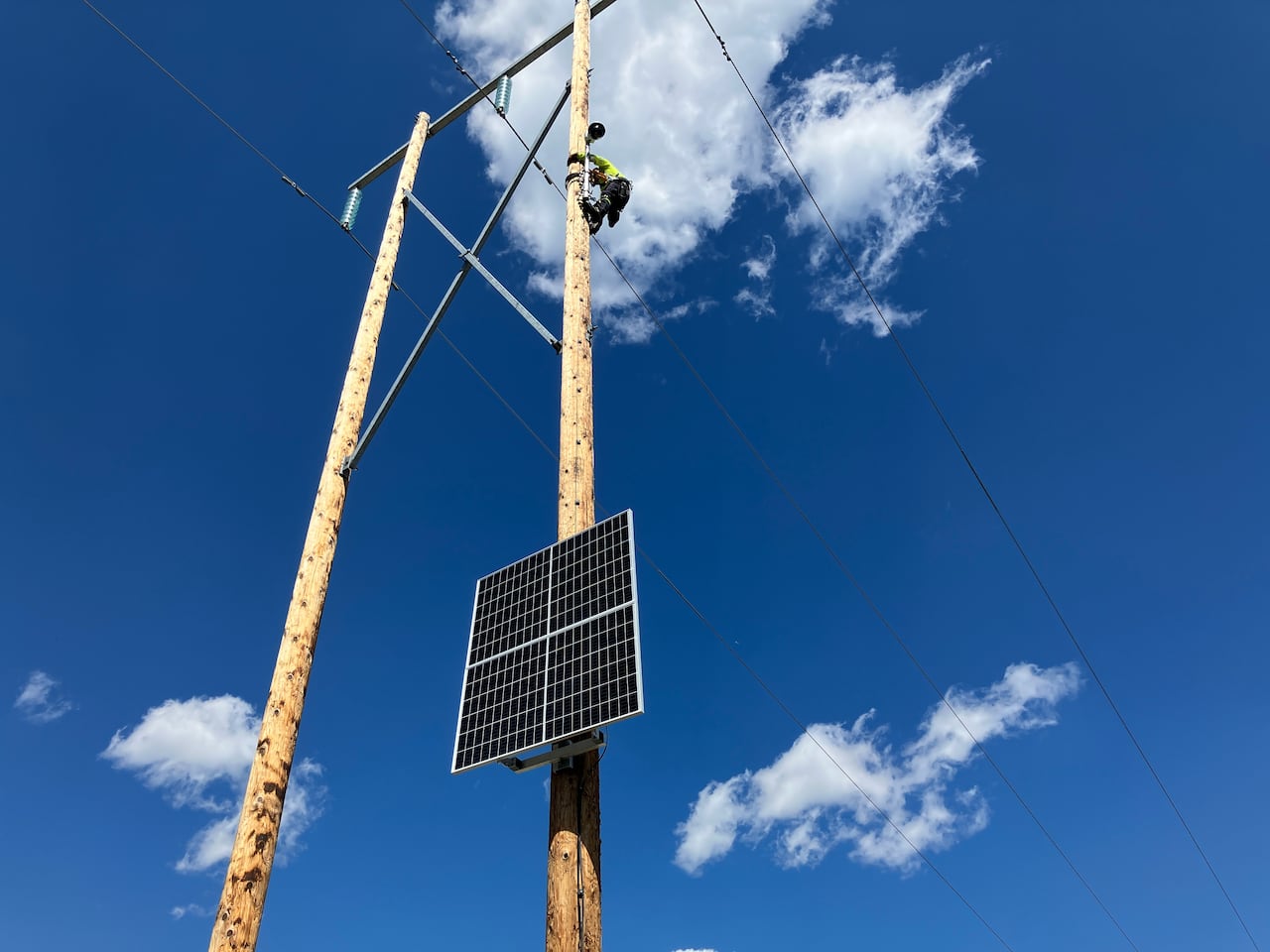 An AltaLink camera in the Bow Valley is being retrofitted by a worker with AI detection software