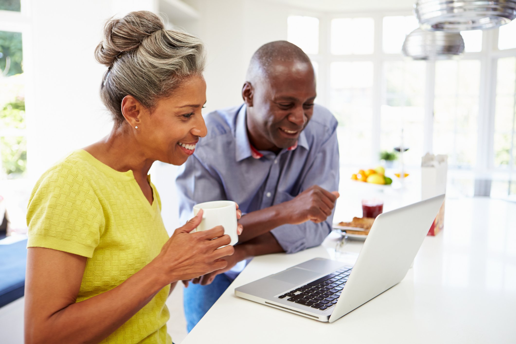 Two people looking at laptop together in kitchen.
