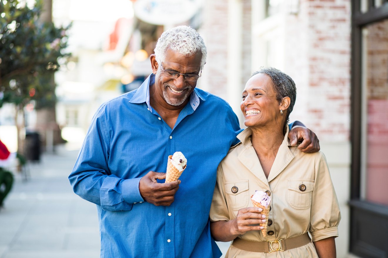 Two people walking down the street, eating ice cream.