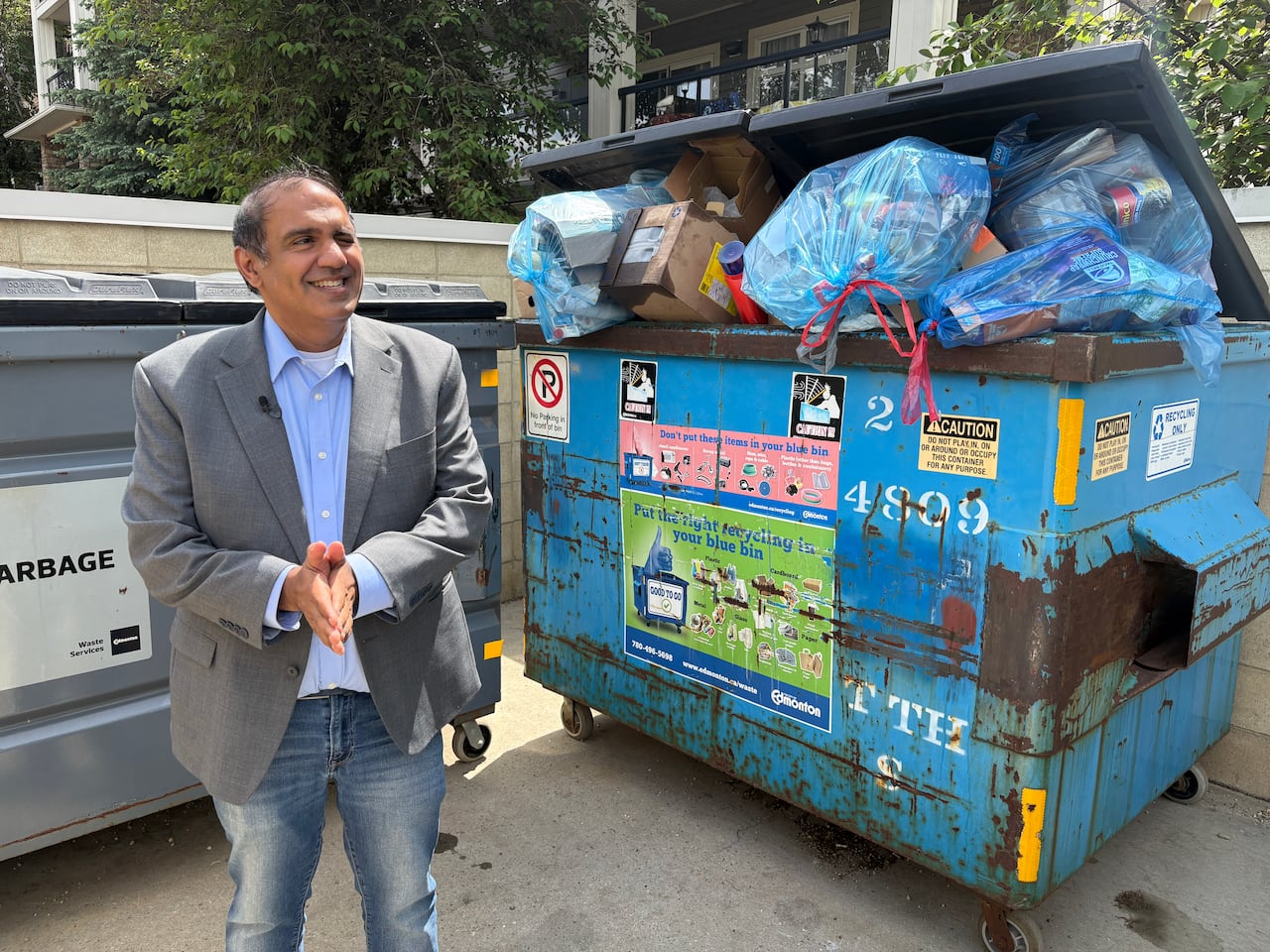 Man stands in front of overfull recycling bin