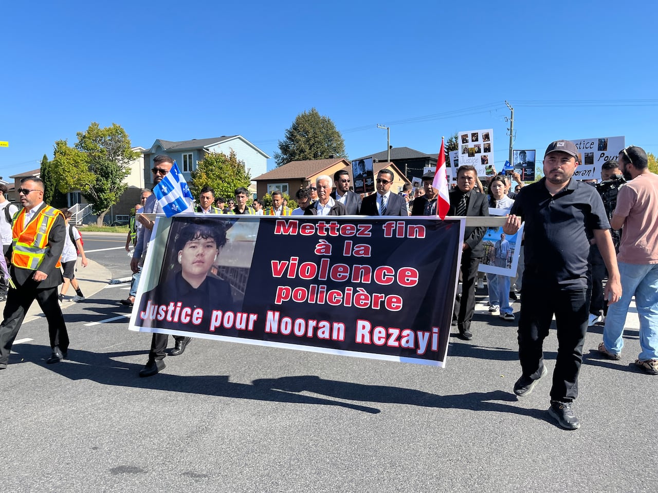 A group of people hold up a large banner calling for justice for Nooran Rezayi
