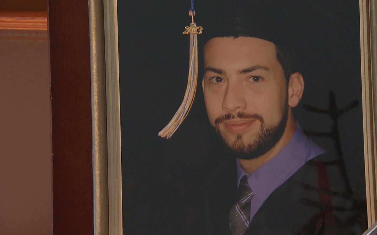 Graduation photo of young man with beard and mustache. 