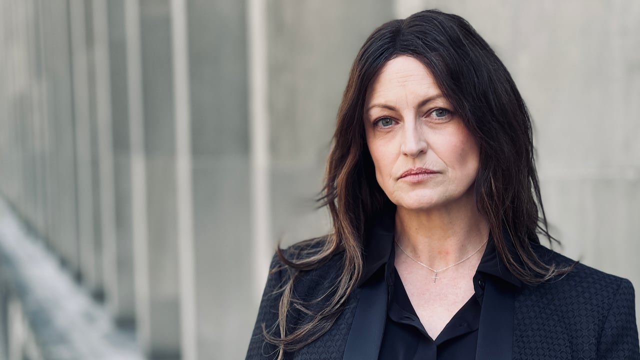A woman stands to the side, looking at the camera.