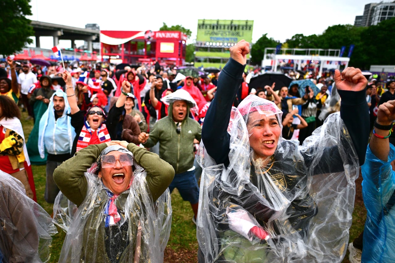 Fans in plastic ponchos and Panama gear clutch their heads and put their arms in the air.