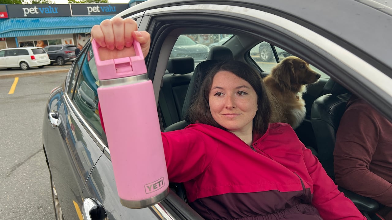 A woman holding a large pink water bottle.