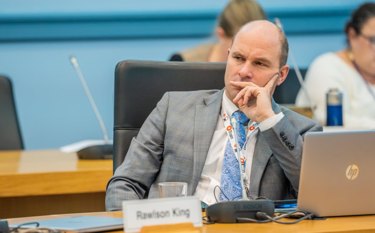 A city councillor sits at their desk and listens during a meeting.