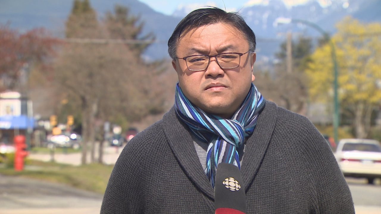 An East Asian man is seen speaking outdoors.