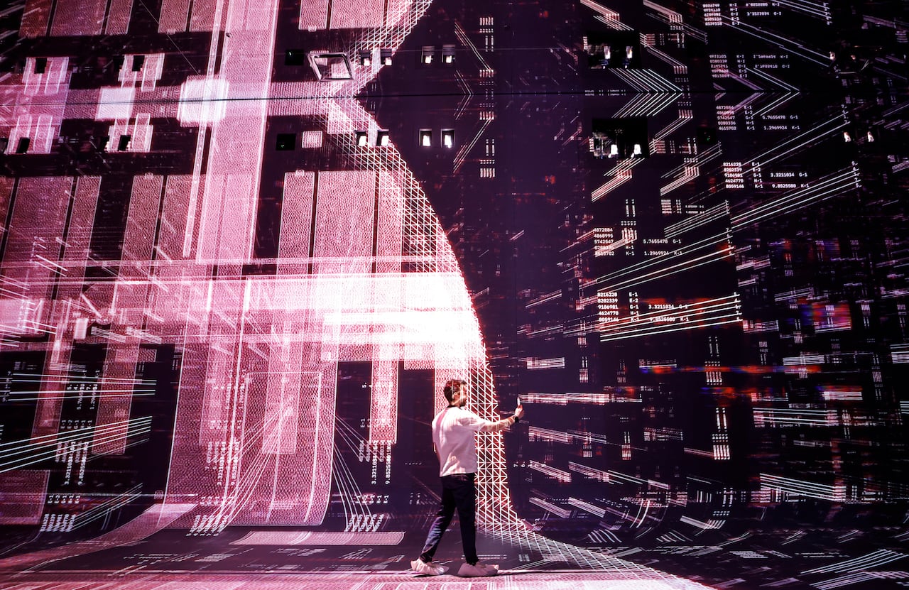 man inputting code into a computer that fills the walls of the room.