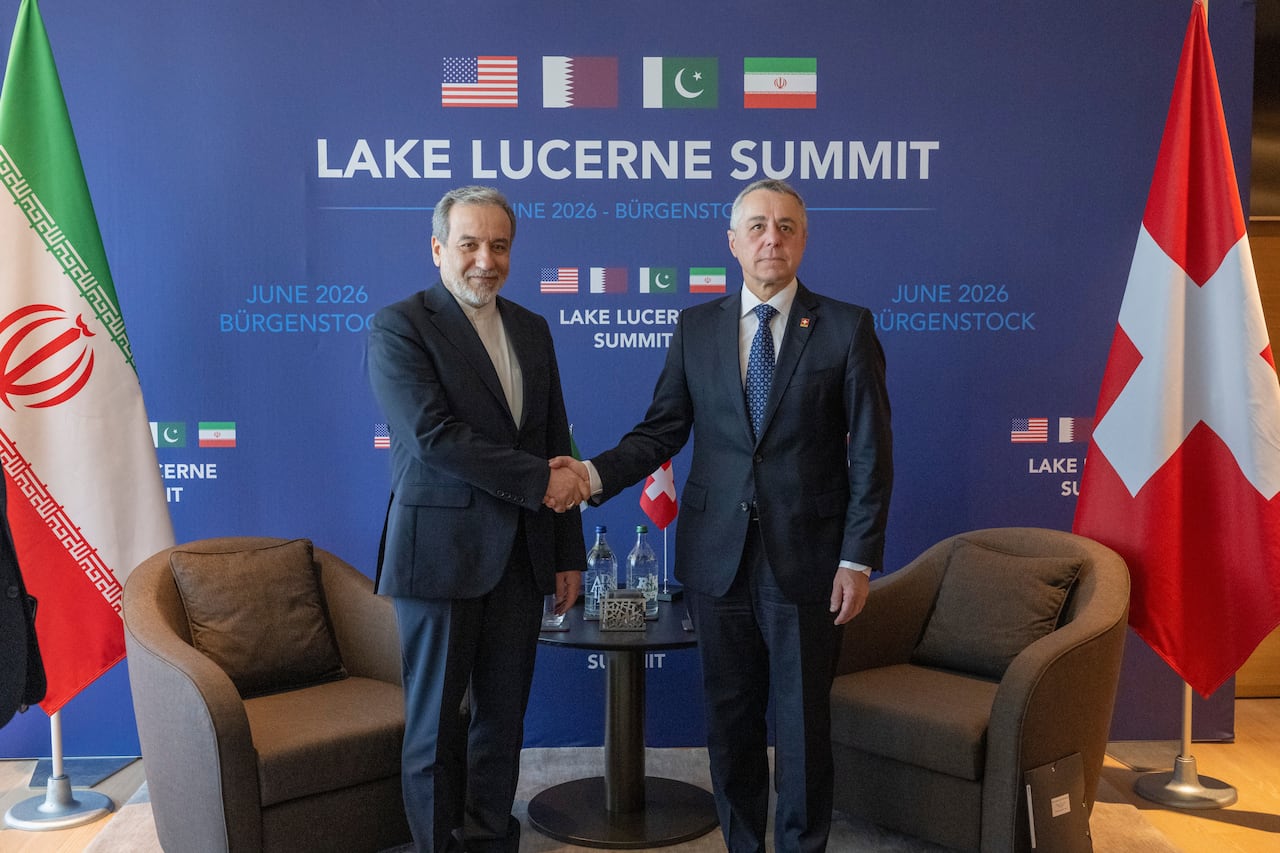 Two men in suits stand up to shake hands.