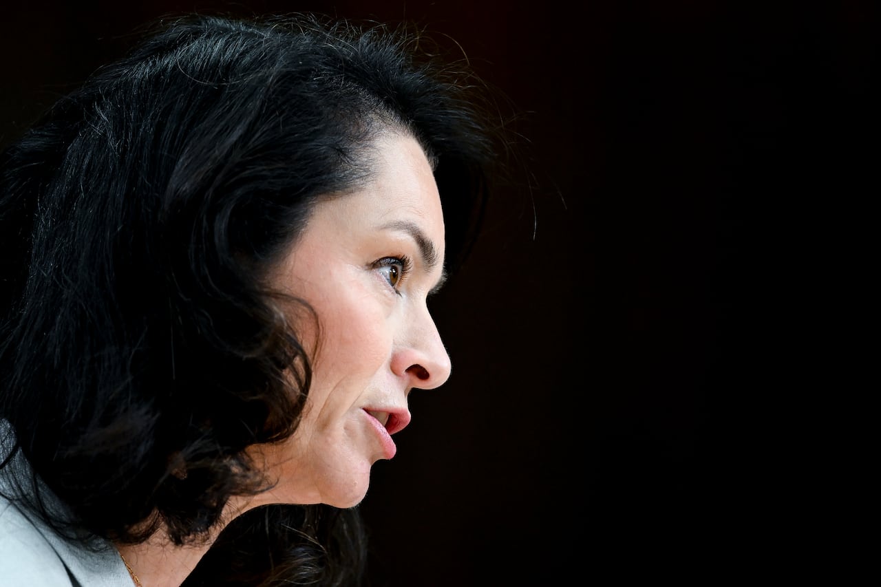 A closeup of a woman, seen in profile, against a black background.