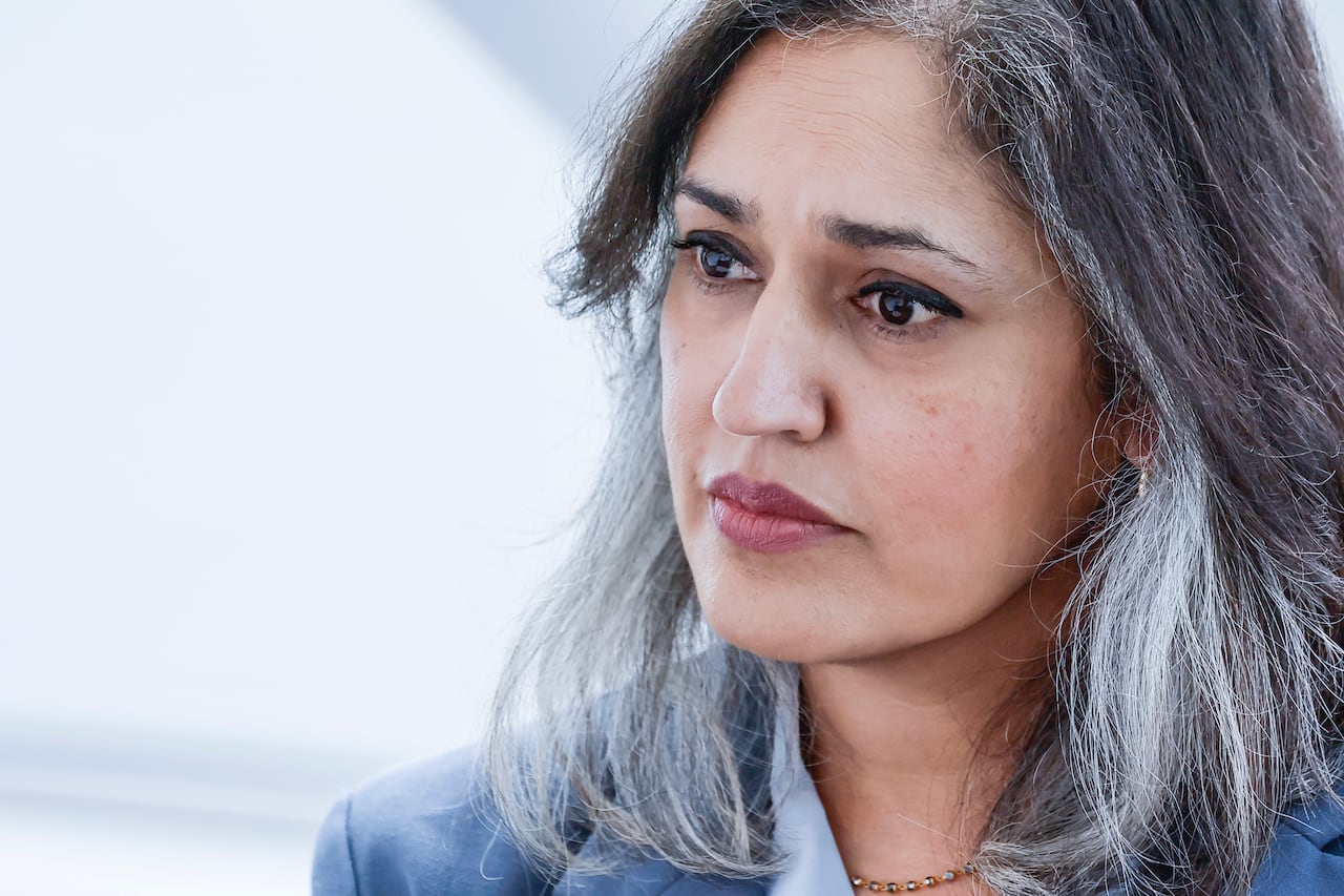 A woman with grey-brown hair is shown looking forward.