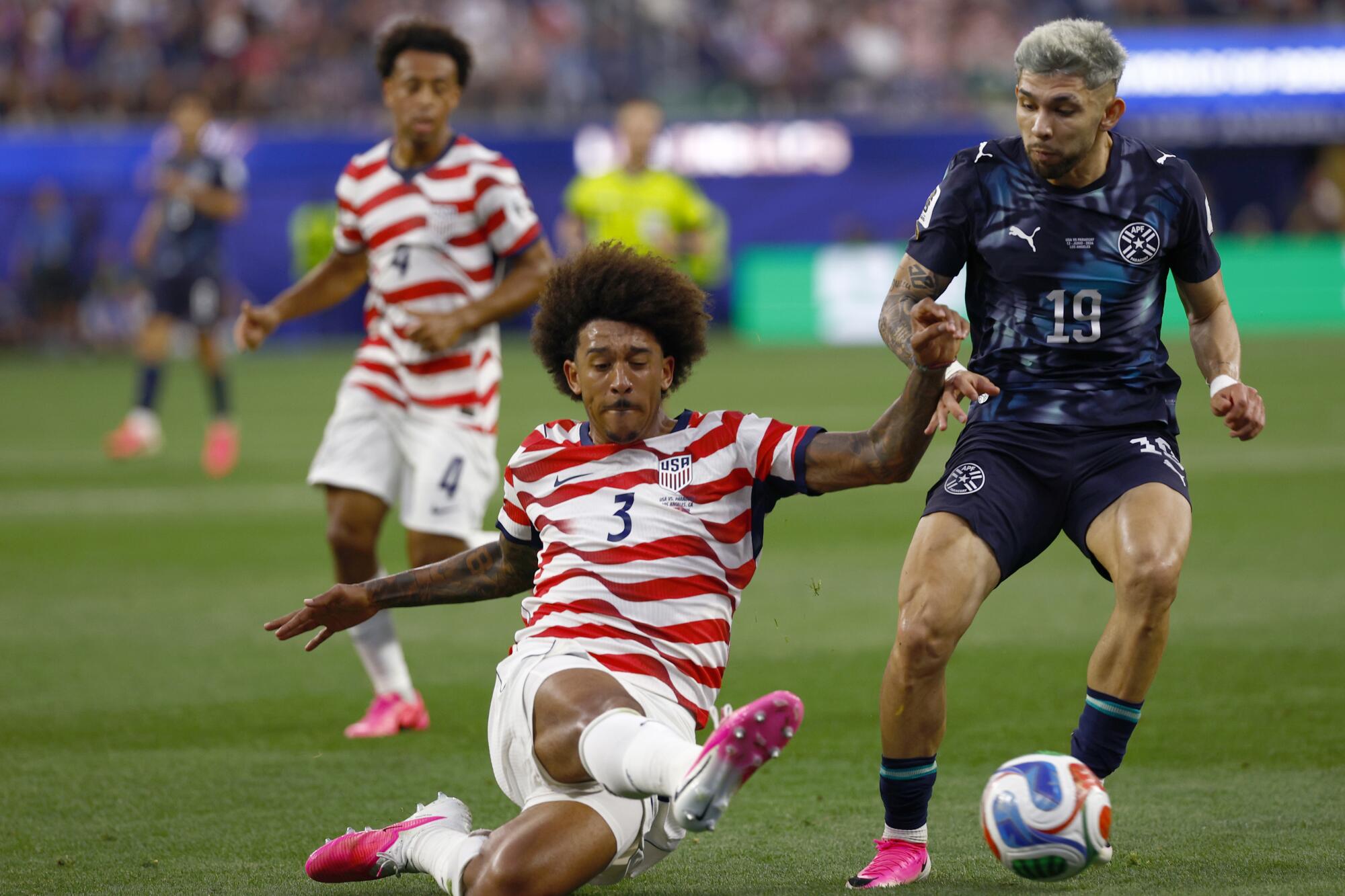 U.S. defender Chris Richards kicks the ball in front of Paraguay forward Julio Enciso while Tyler Adams looks on.