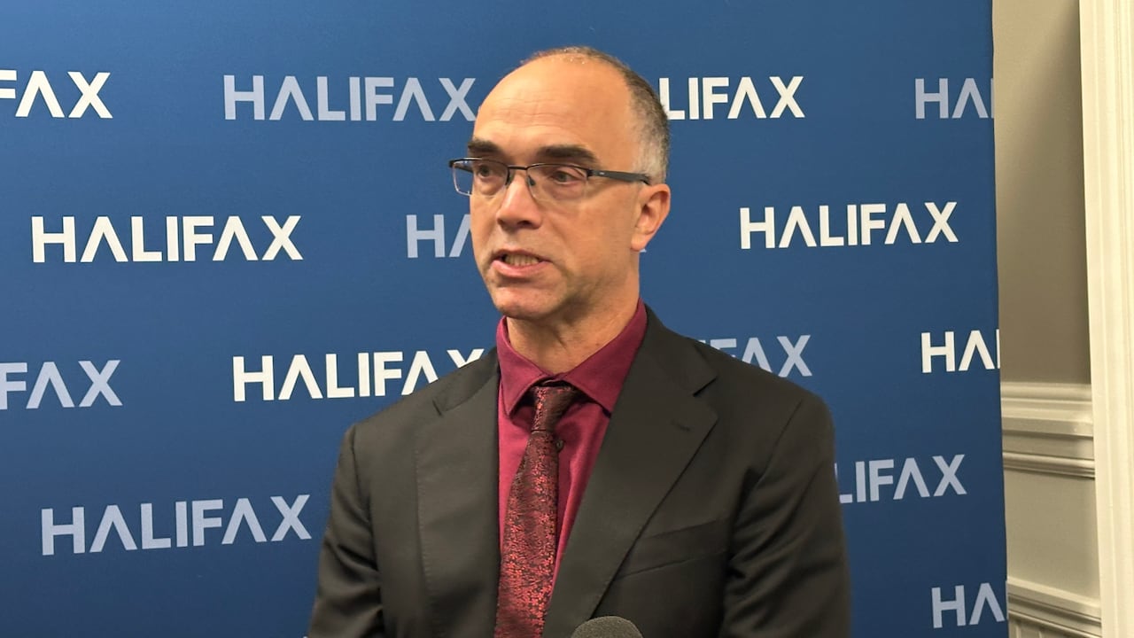 Man in suit standing against a backdrop written HALIFAX