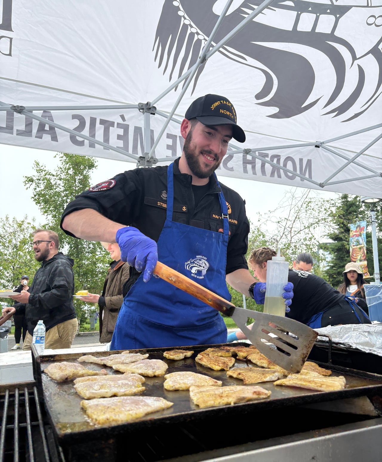 Luc Steele, a volunteer from the Canadian Armed Forces, flips out as he dishes out fish at the North Slave Métis Alliance's Indigenous Peoples Day event.