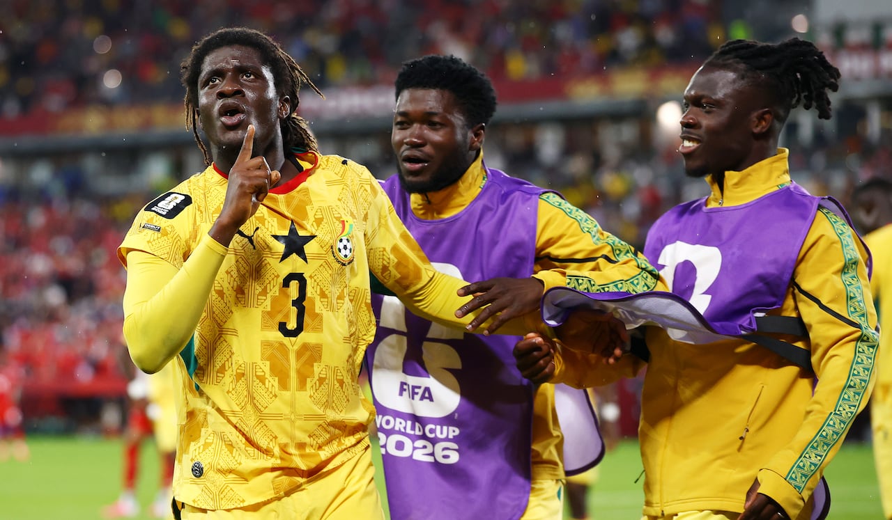 Ghanaian soccer players in bright yellow kits celebrate a goal.