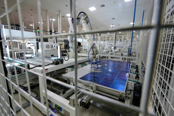 A robot places solar cells on a glass panel at a ReNew manufacturing plant on the outskirts of Jaipur, India, Aug. 21, 2025. (AP Photo/Manish Swarup, File)