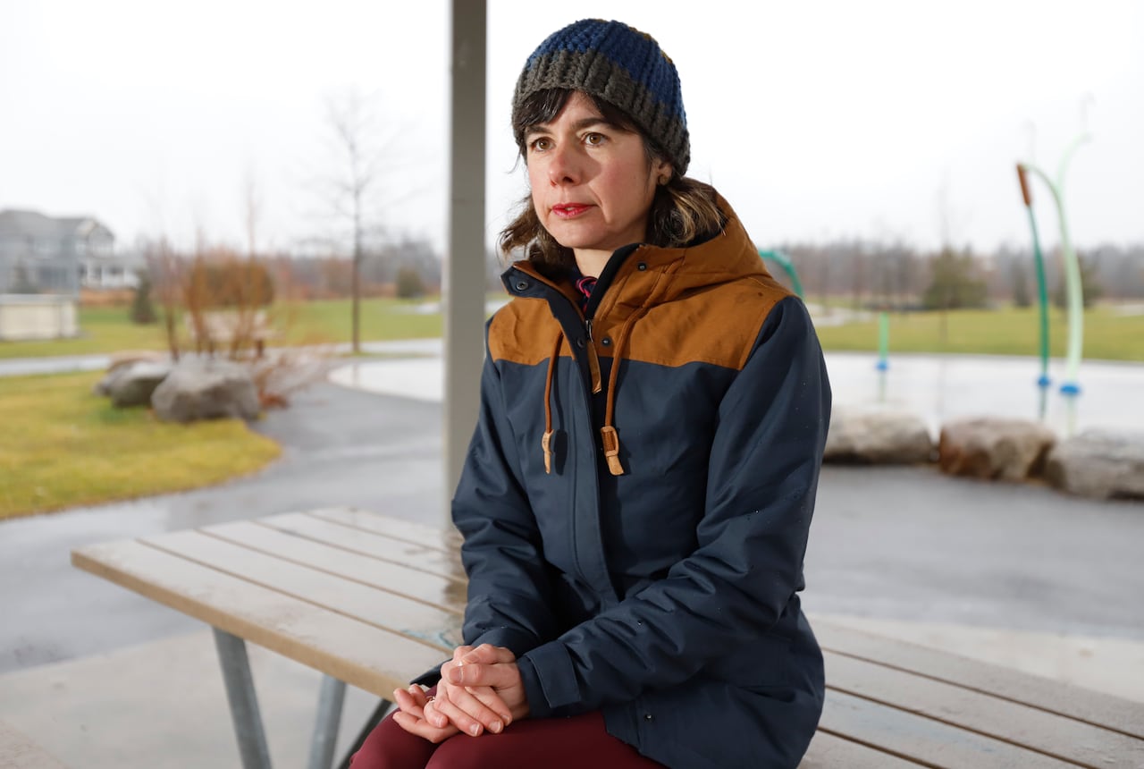 A woman sits on a bench in a playground.