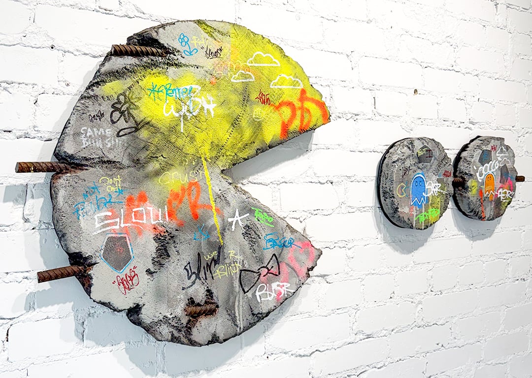 A concrete wall sculpture showing a Pac-Man eating two circles.