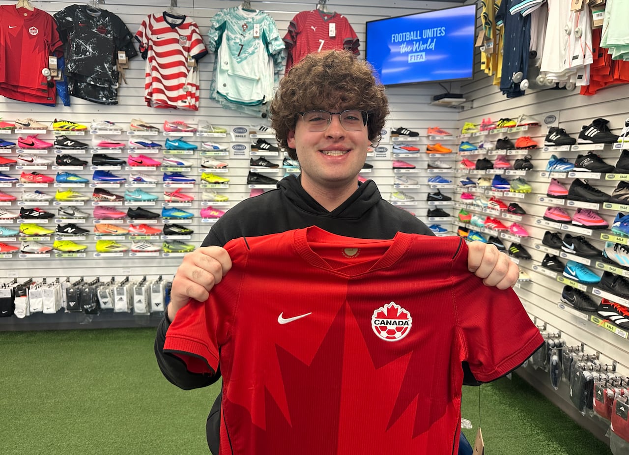 A man holds up a jersey.