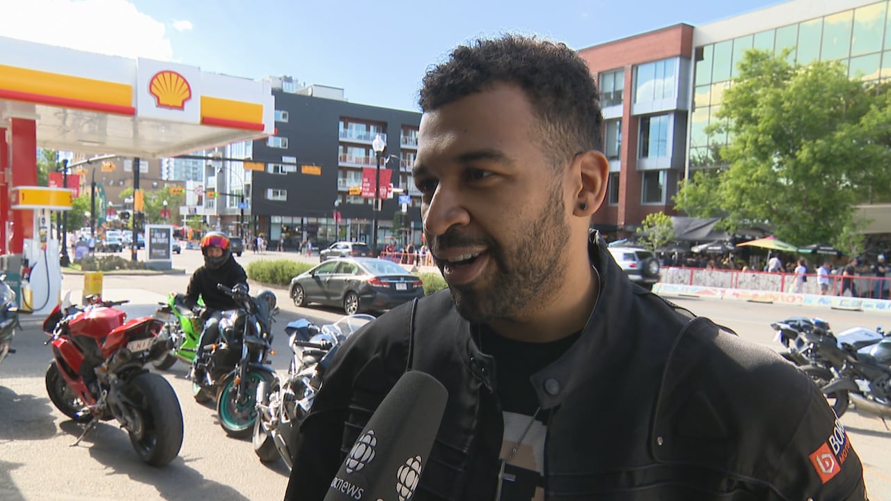 A man in front of motorcycles at a gas station.
