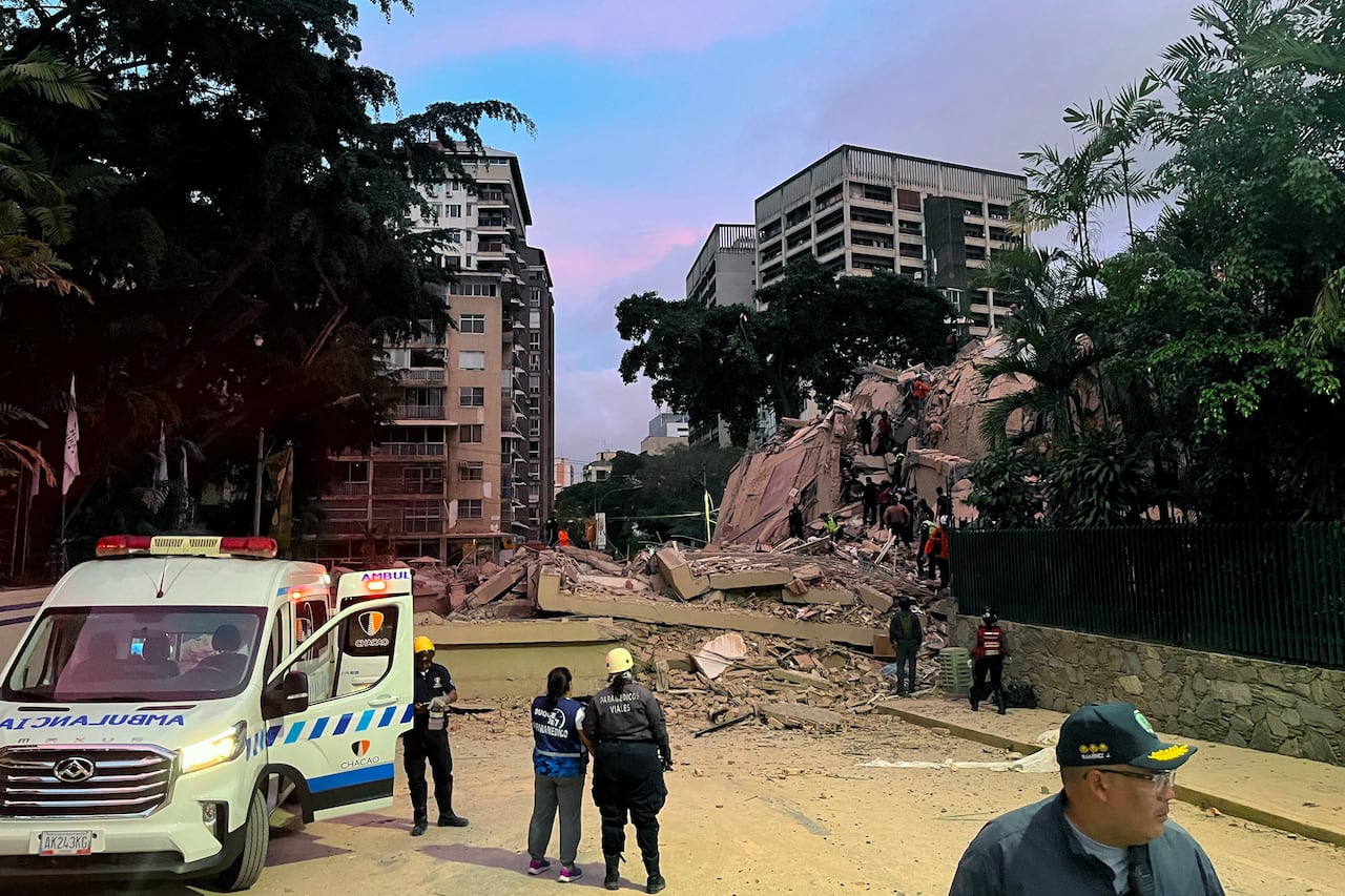 Emergency personnel looks at a half collapsed building