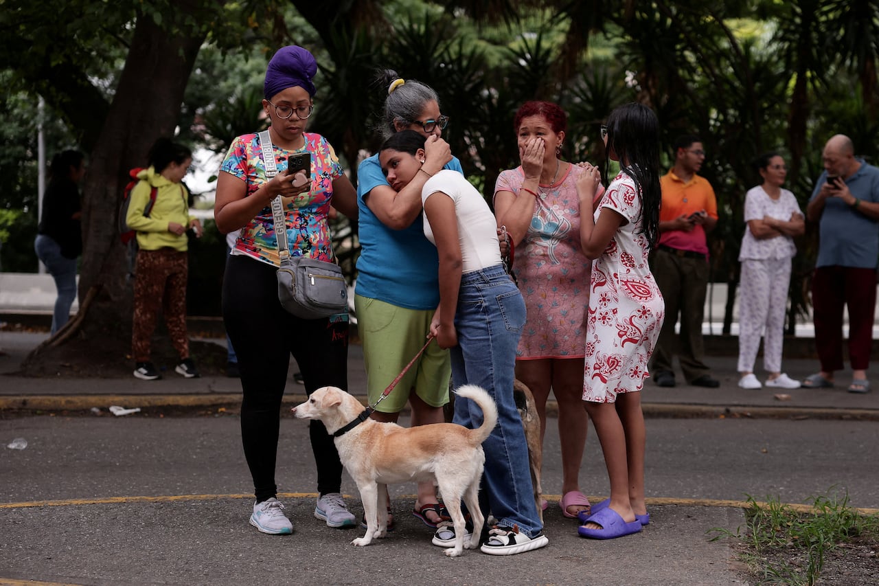 People stand in the street, hugging, with a dog