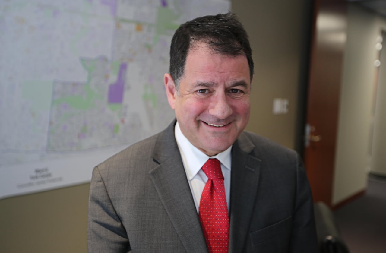 A man with a brown suit and brown hair smiling.