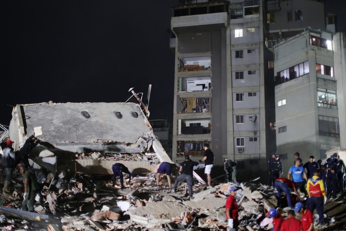People standing amid rubble, with a multistory building in the background