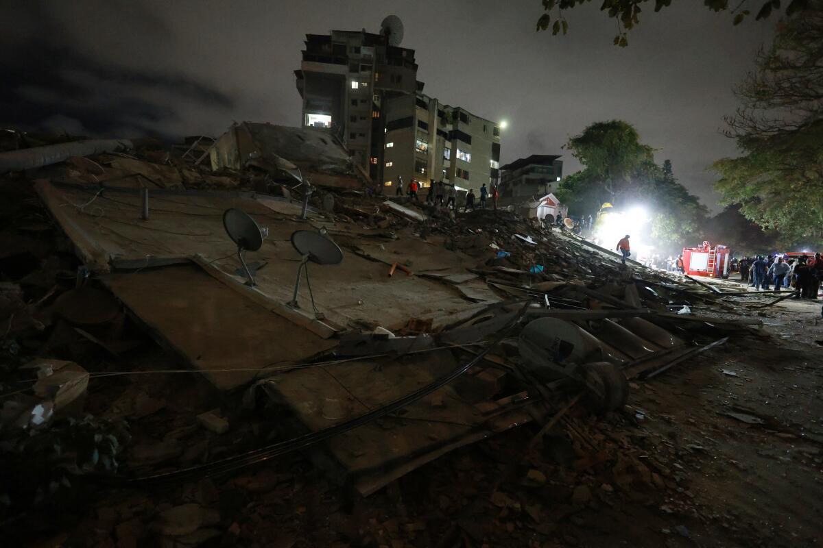 Rescue crews in a brightly lighted area search for survivors in the dark
