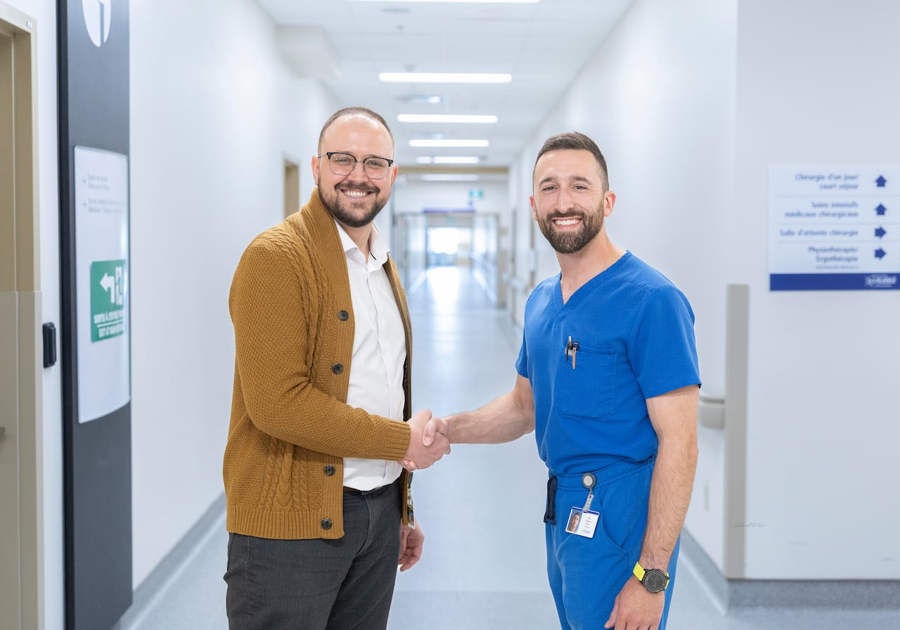 Doctor shaking hands with a man in a brown cardigan in a hospital.