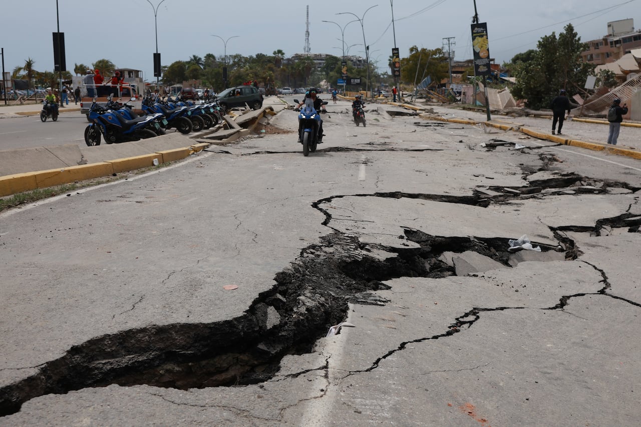 Motorcyclists ride along a road cracked by earthquakes that struck La Guaira, Venezuela, a day earlier, Thursday, June 25, 2026. (AP Photo/Javier Campos)