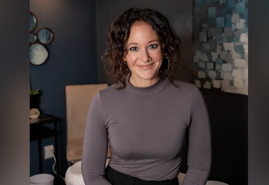 A woman with dark curl hair smiles at the camera