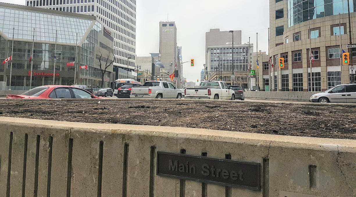 Concrete barricades block pedestrians from crossing a street.