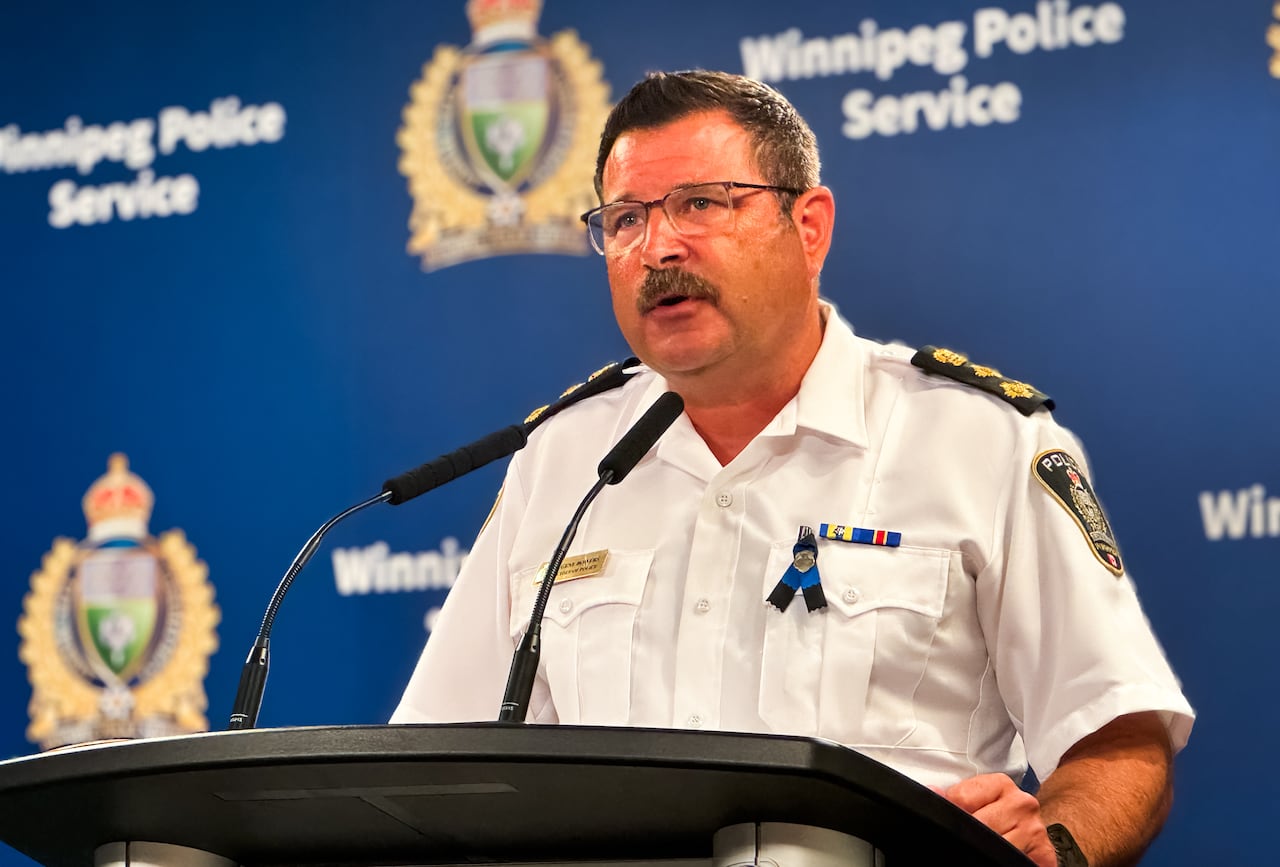 A man in a police uniform speaks at a podium.