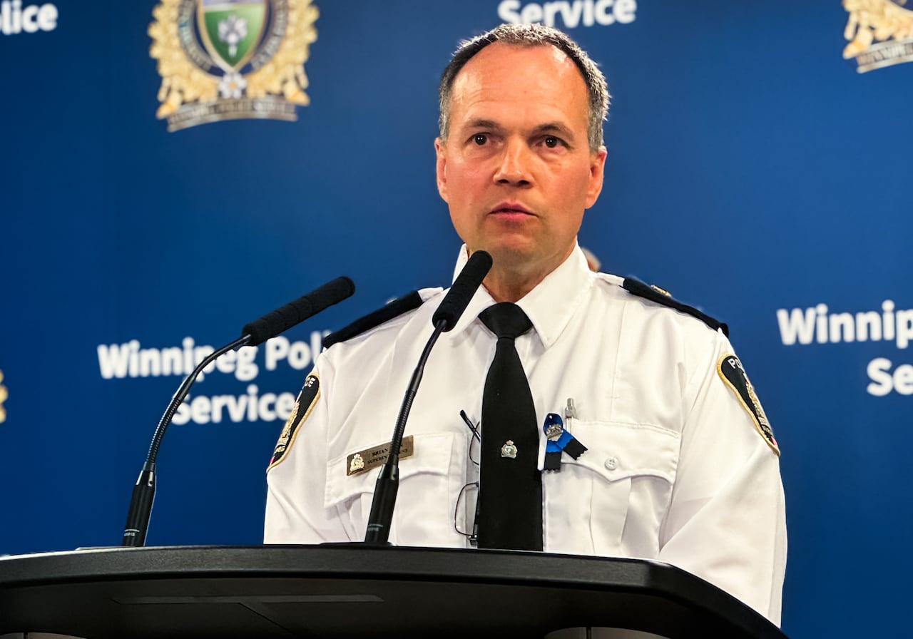 A man in a police uniform speaks at a podium.