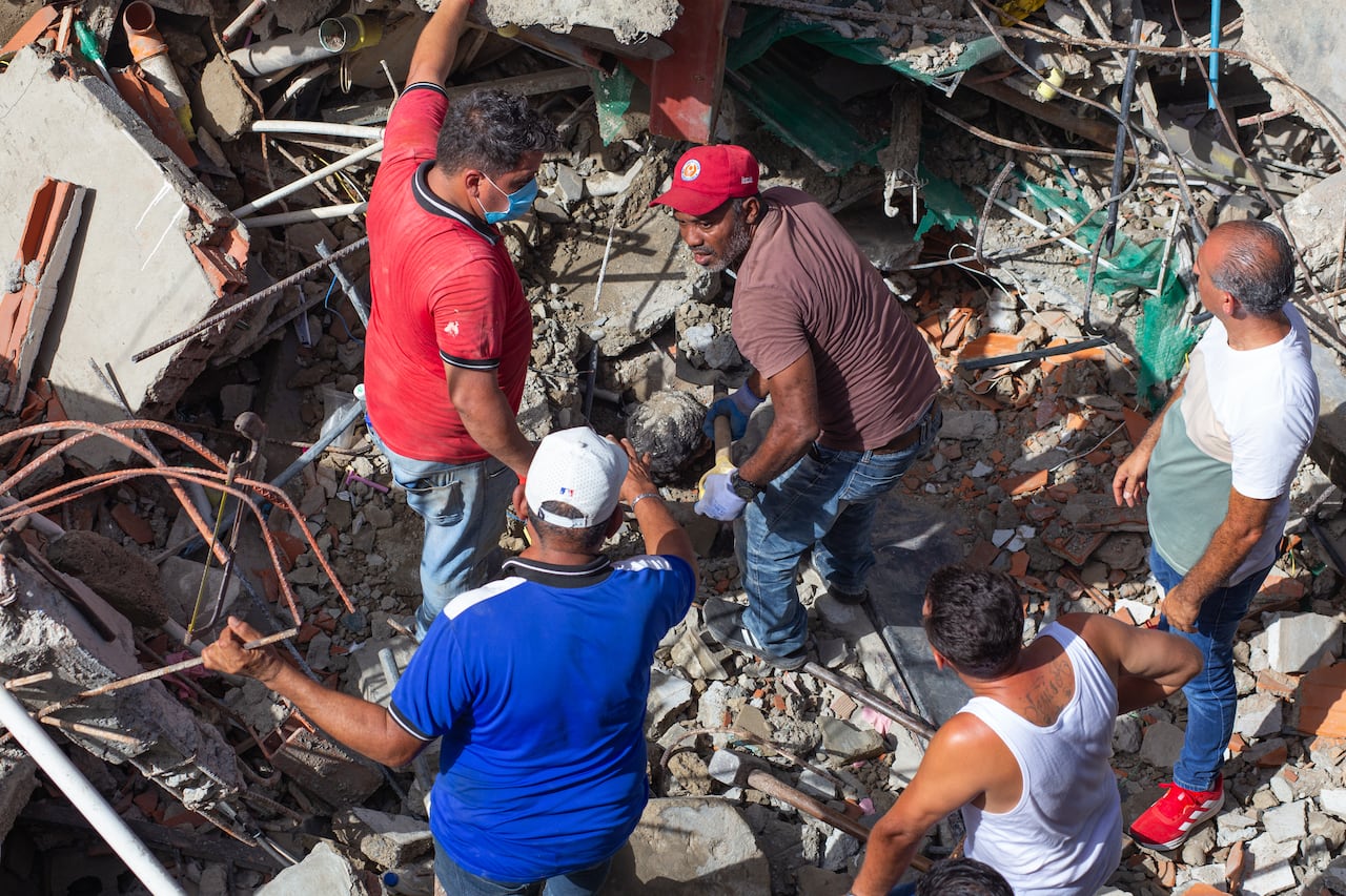 Five men stand in the wreckage of a building destroyed by earthquake.