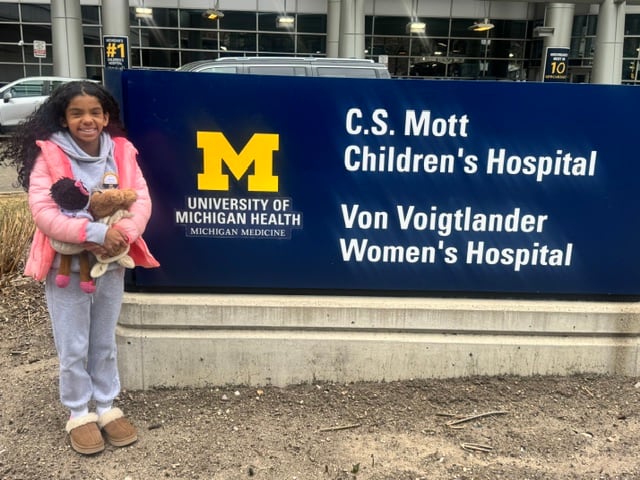 A girl next to hospital sign.
