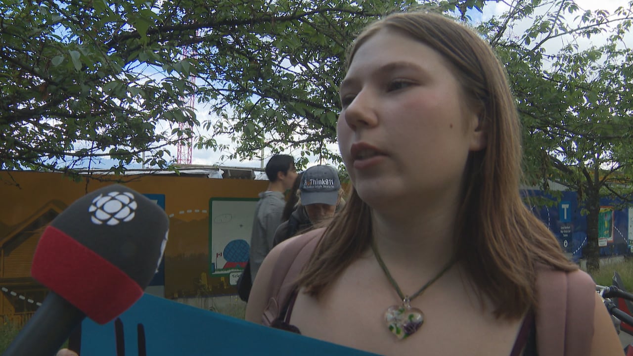 A young woman with long hair speaks into a CBC microphone.