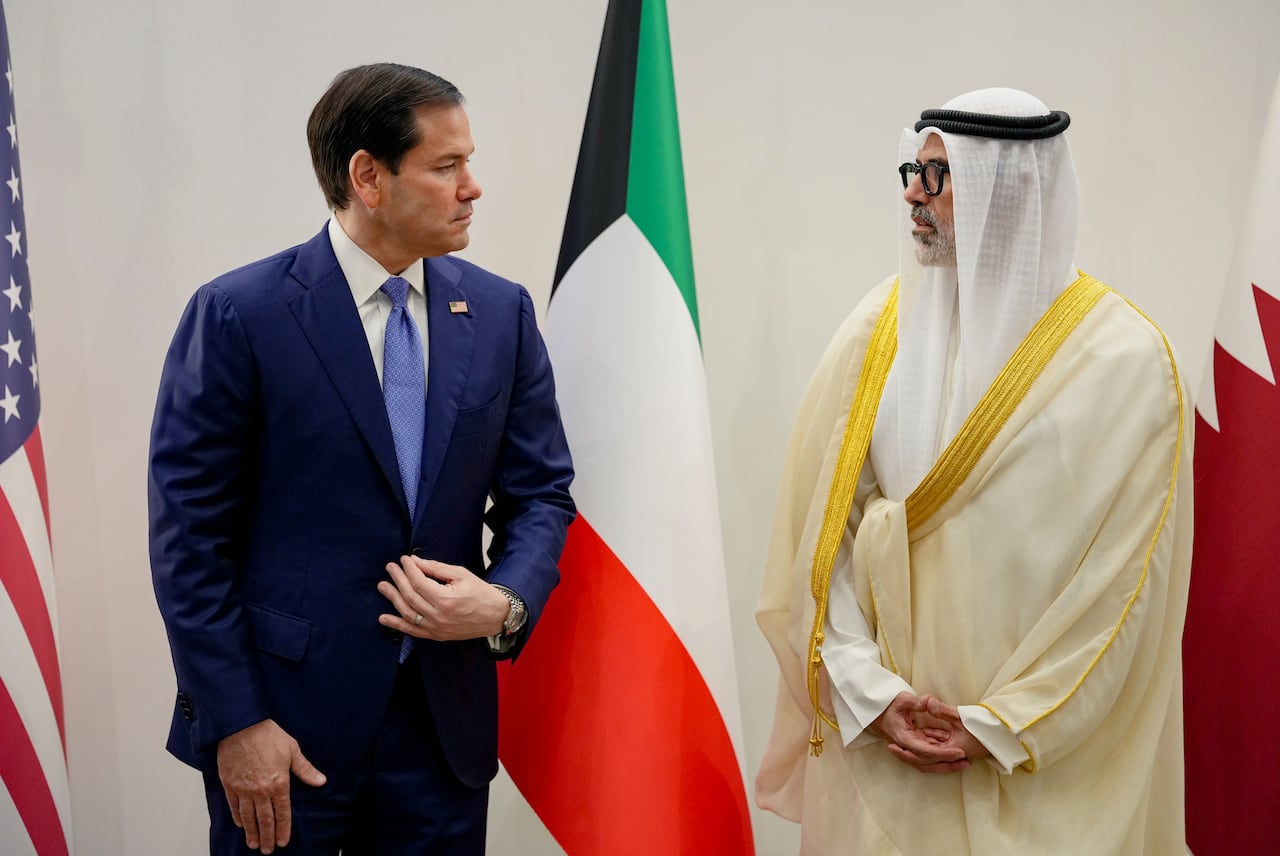 Two men speak in front of flags.